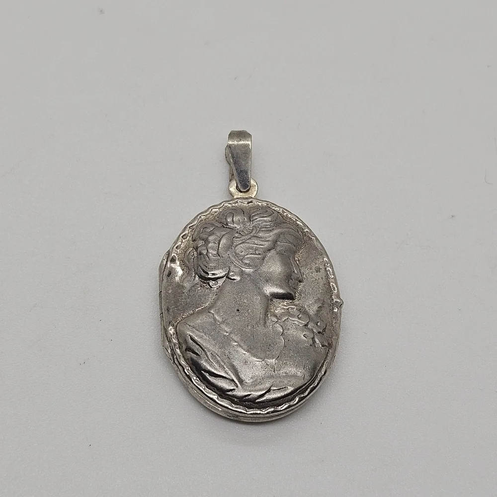 silver tone oval shaped locket style pendant with woman's silhouette